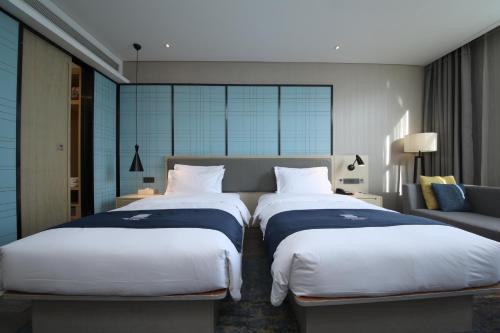 武漢市にあるEcharm Hotel Wuhan Jianghan Road Walking Streetのベッド2台とソファがあるホテルの部屋
