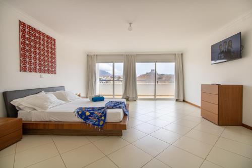 a bedroom with a bed and a large window at Sky Mariposa sospesa sul mare in Mindelo