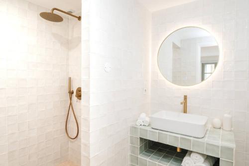 a white bathroom with a sink and a mirror at La Demeure de la Cité by Jean Bacou in Carcassonne