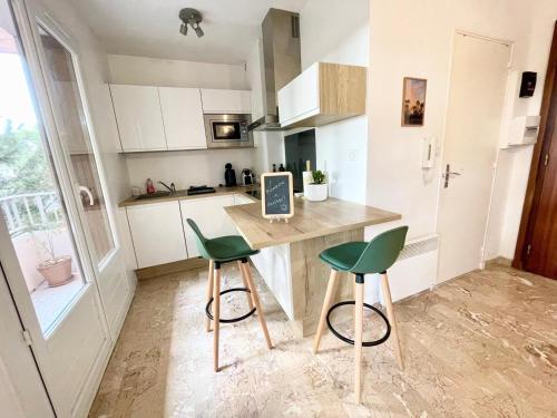 une cuisine avec une table et deux chaises vertes dans l'établissement Studio Portissol, à Sanary-sur-Mer