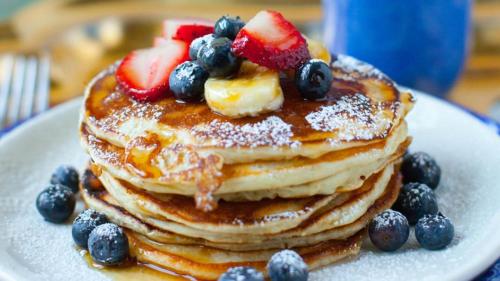 a stack of pancakes with fruit on top on a plate at Mary Apartments in Stalida