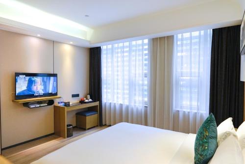 a hotel room with a bed and a television at Paco Hotel Tiyuxilu Metro Guangzhou-Free Shuttle Bus during Canton Fair&5 Min walk to Canton Fair Buyer Registration Store in Guangzhou