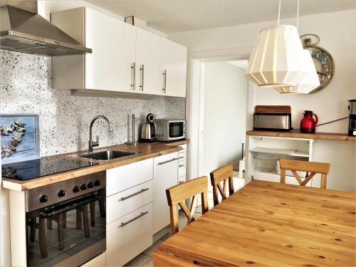 une cuisine avec des armoires blanches et une table en bois dans l'établissement Ostseeinsel, à Kellenhusen