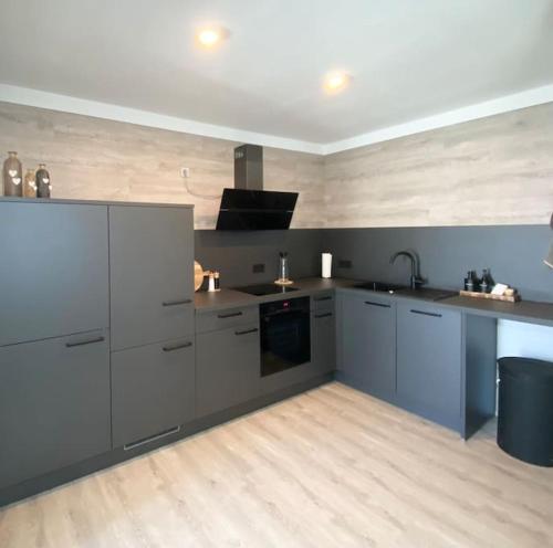 a large kitchen with gray cabinets and blue counters at Oh my Deer nagelneues Appartement für Zwei in Tauberbischofsheim