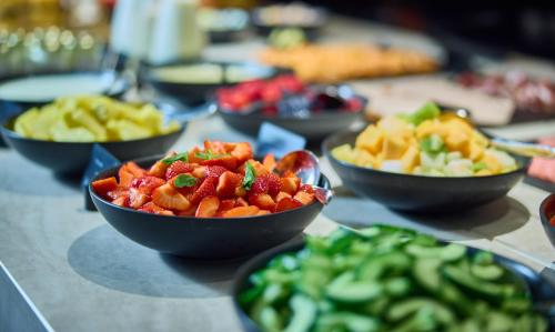 a table topped with bowls of fruits and vegetables at Cardo Brussels, Autograph Collection in Brussels