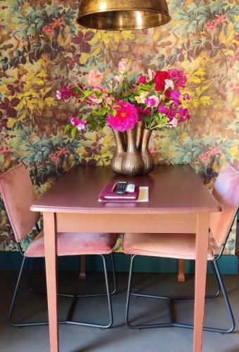 a vase of flowers on a table with two chairs at Vakantiehuisje Bellefleur huisje Daisy in Roderwolde