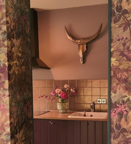 a bathroom with a sink and a vase of flowers at Vakantiehuisje Bellefleur huisje Daisy in Roderwolde