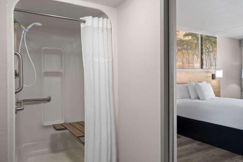 a bathroom with a bed and a shower with a shower curtain at Days Inn by Wyndham Conway in Conway