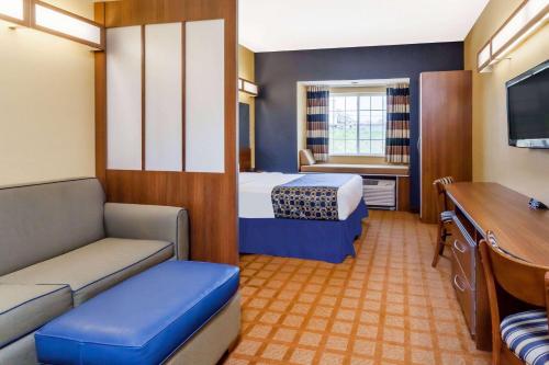 a small hotel room with a bed and a couch at Microtel Inn & Suites in Dickson City