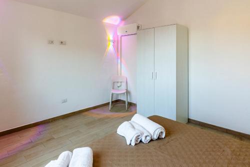 une pièce avec des serviettes blanches sur le sol et une chaise rose dans l'établissement LeaRooms, à Olbia