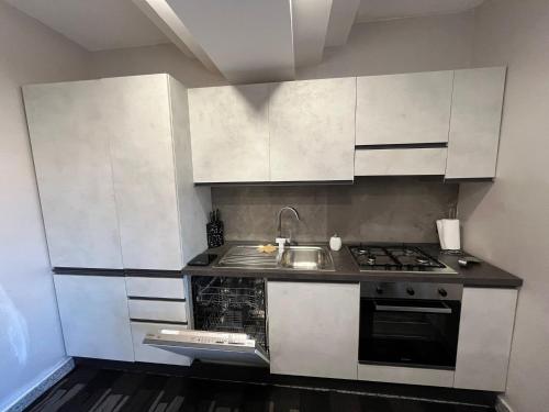a kitchen with white cabinets and a sink and a stove at Domus Teresae in Avezzano