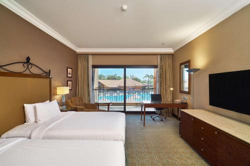 a hotel room with two beds and a flat screen tv at Hilton Alexandria King's Ranch Hotel in Alexandria