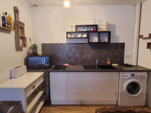 une cuisine avec un évier et une machine à laver dans l'établissement Appartement T2 très cosy proche centre ville, à Sorges