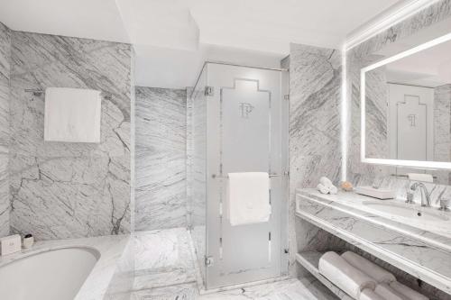 a bathroom with a tub and a sink and a mirror at The Plaza Doha, LXR Hotels & Resorts in Doha