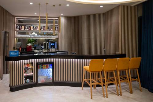 a bar with four chairs and a refrigerator at Hampton By Hilton Istanbul Merter in Istanbul