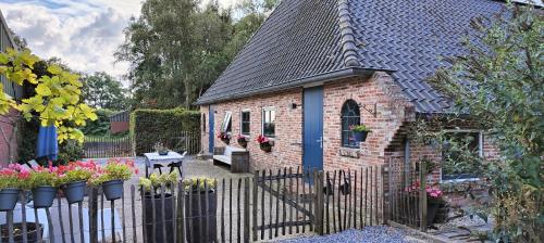a small brick building with a fence and flowers at Vakantiehuisje Bellefleur huisje Daisy in Roderwolde