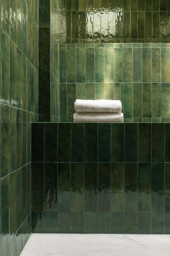 a green tiled bathroom with two towels on a shelf at Dare Lisbon River in Lisbon