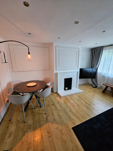 a dining room with a table and chairs and a fireplace at Wembley, Cosy 2 Bed Apa, Next to the park in Harrow on the Hill