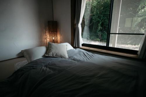 a bed sitting in a room with a window at River & Forest Genpuan Sauna Drum bath BBQ Hearth in Shibukawa