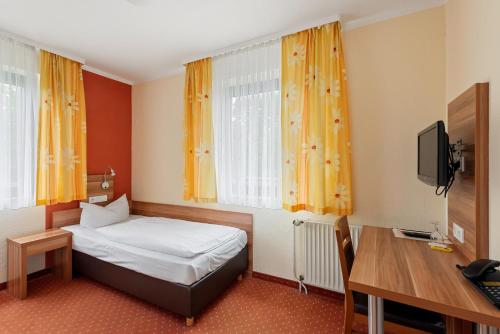 a bedroom with a bed and a desk and a television at Jägerheim in Nürnberg