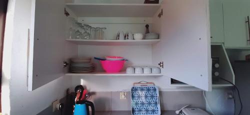 a kitchen with a white cabinet with dishes and utensils at Baleia Azul - House 7A in Ponta Mamoli