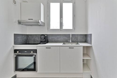 une cuisine blanche avec un évier et une cuisinière dans l'établissement Studio charmant tout équipé Paris Montreuil - II, à Montreuil