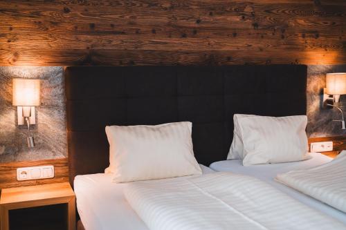 two beds with white pillows in a bedroom at Hotel Rauscher - Das Naturteichparadies in Bad Hofgastein