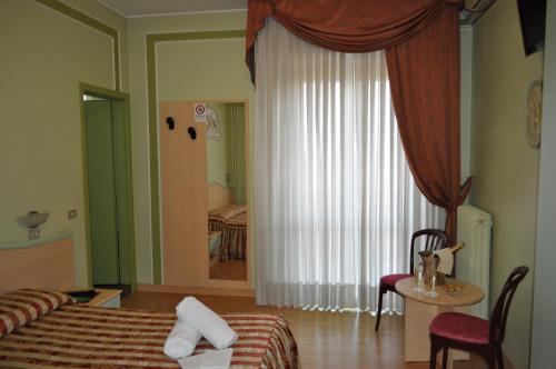 a bedroom with a bed and a table and a window at Hotel Alsazia in Sirmione