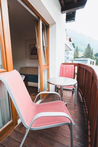 a balcony with a pink chair and a table at Hotel Rauscher - Das Naturteichparadies in Bad Hofgastein