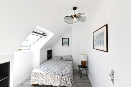 une chambre blanche avec un lit et un ventilateur de plafond dans l'établissement St Gildas de Rhuys - Maison 10 personnes avec 5 chambres, 900 m plage et 500 m centre bourg, à Saint-Gildas-de-Rhuys
