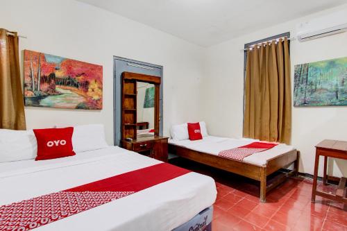 a bedroom with two beds and a table and a mirror at Hotel O Homestay Alqid Syariah in Yogyakarta