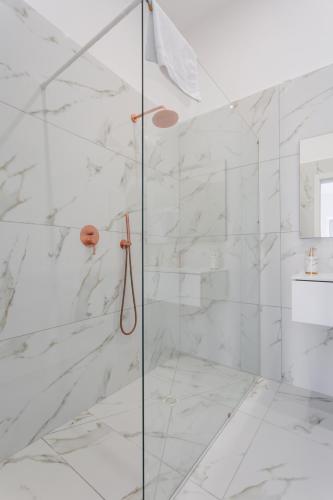 a bathroom with a shower with white marble walls at Golden Suites by Dimorra in Naples