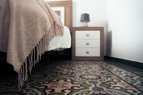 a bedroom with a bed and a dresser and a rug at Casa Herrete in Medina Sidonia
