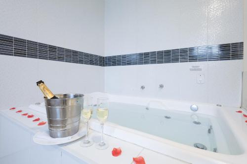 a bathroom with a tub with a bottle of champagne and glasses at Sumaré Park Hotel in Sumaré