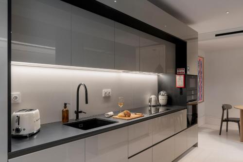 a kitchen with white cabinets and a sink with a toaster at Luxury Garden Apartment at Savoy Insular in Funchal