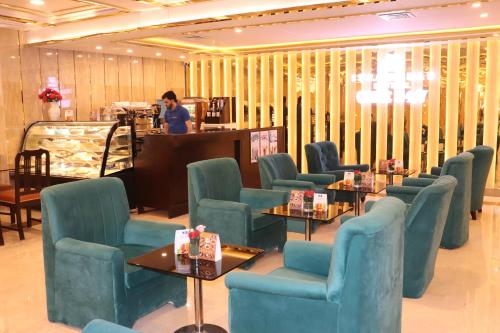 a waiting room with blue chairs and a woman at a counter at Islamabad Hotel in Islamabad