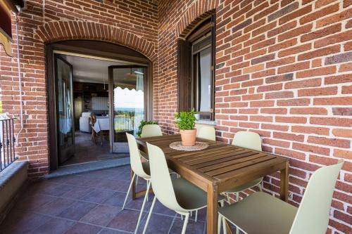 a wooden table with white chairs and a brick wall at Villa Bruno Selvago in Lessona in Lessona