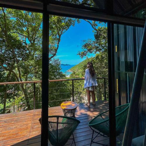 a woman standing on the balcony of a house at Chalé Sattva - Vista Mar - Florianópolis - SC - Brasil in Florianópolis
