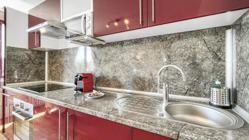 - une cuisine avec un évier et des placards rouges dans l'établissement Homey Belleza - Hypercentre, proche Geneve, proche train et tram, à Annemasse