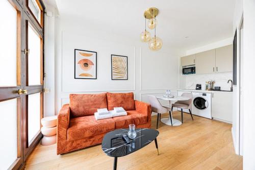 un salon avec un canapé orange et une table dans l'établissement Appart 1 chambre#Tour Eiffel#Champ de Mars#Paris 7, à Paris