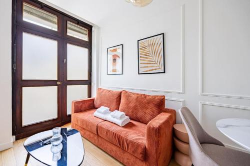 un salon avec un canapé orange et une table dans l'établissement Appart 1 chambre#Tour Eiffel#Champ de Mars#Paris 7, à Paris