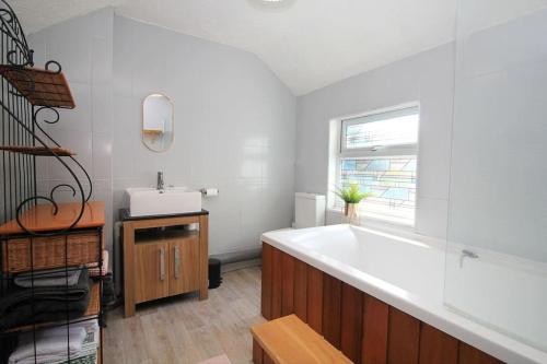 a bathroom with a large white tub and a sink at Cottage in Walton on the Naze in Walton-on-the-Naze