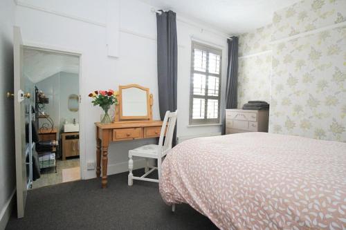 a bedroom with a bed and a desk with a mirror at Cottage in Walton on the Naze in Walton-on-the-Naze