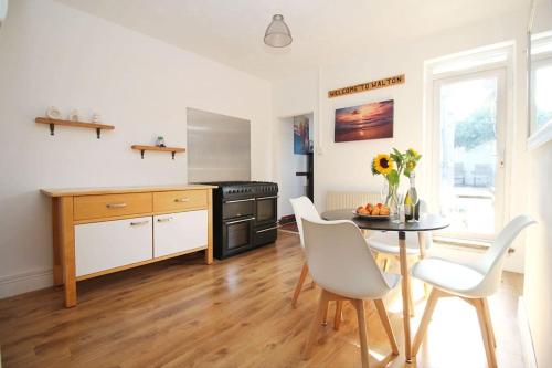 a kitchen with a table and white chairs and a table and a tablektop at Cottage in Walton on the Naze in Walton-on-the-Naze