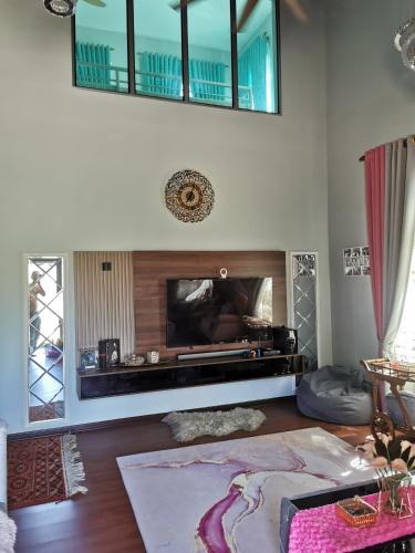 a living room with a fireplace and a tv at Teratak Dusun NadzYan in Bukit Selambau