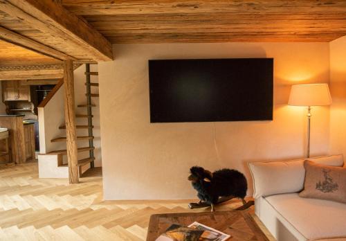 a living room with a couch and a tv on the wall at Modernes Chalet mit Sauna, Whirlpool und Bergblick in Sankt Stephan