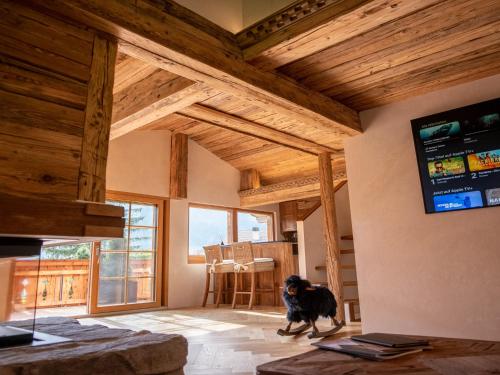 a dog standing in a living room with a tv at Modernes Chalet mit Sauna, Whirlpool und Bergblick in Sankt Stephan