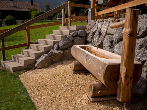 a wooden bath tub sitting next to a stone wall at Modernes Chalet mit Sauna, Whirlpool und Bergblick in Sankt Stephan