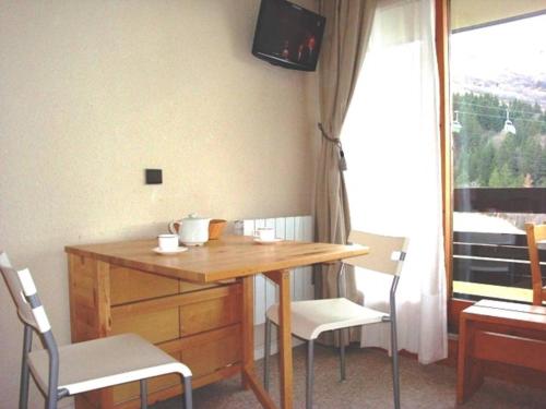 Cette chambre dispose d'une télévision et d'une table avec des chaises en bois. dans l'établissement Studio lumineux avec accès direct aux pistes et à l'ESF - FR-1-356-233, à Valmorel