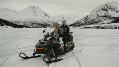 a man and woman riding on a snowmobile on the ice at EIRA Fjord Stay with firepit, snowmobile rental and free snowshoes in Tromsø